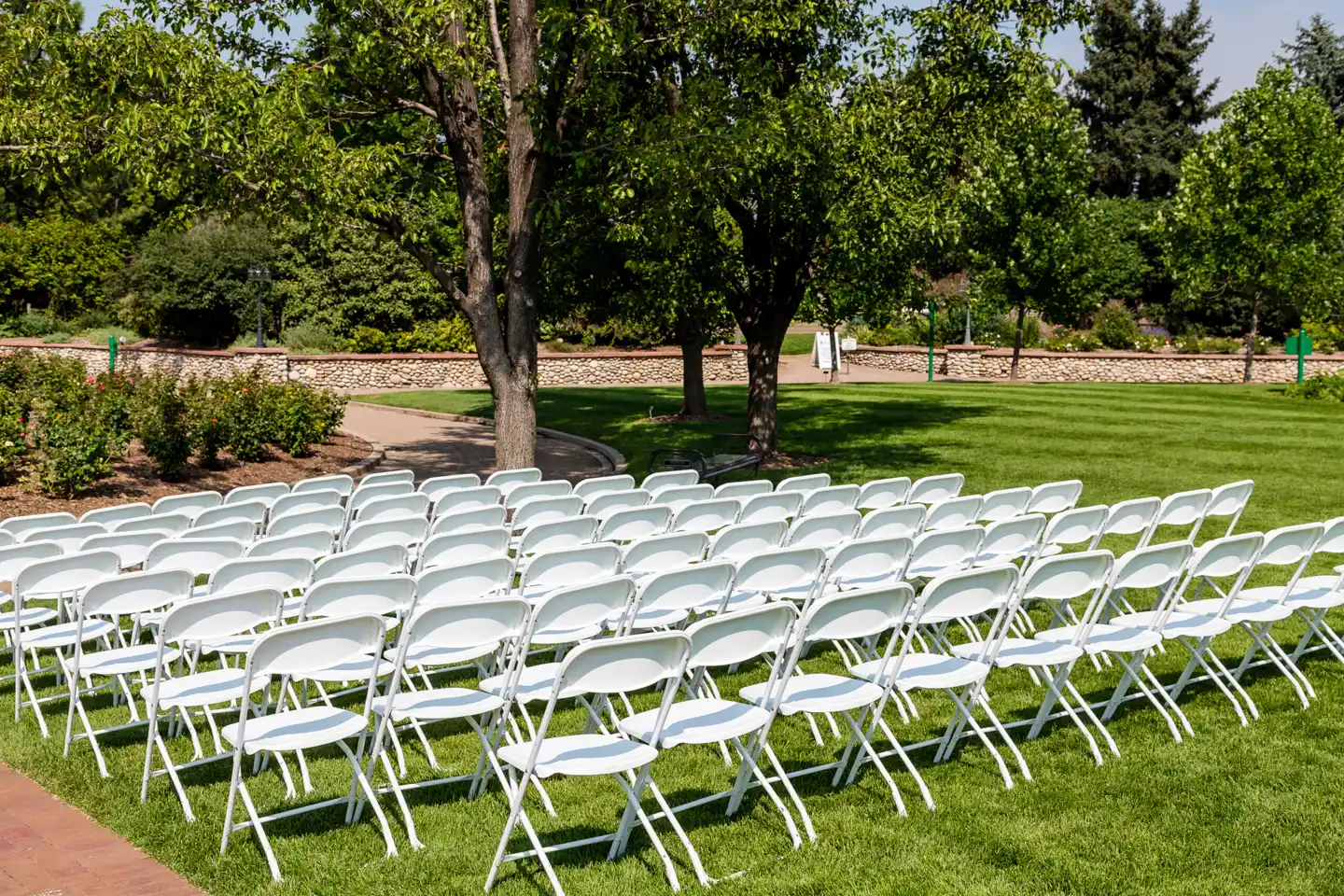 Rows of white folding chairs set up on a lawn for an outdoor event