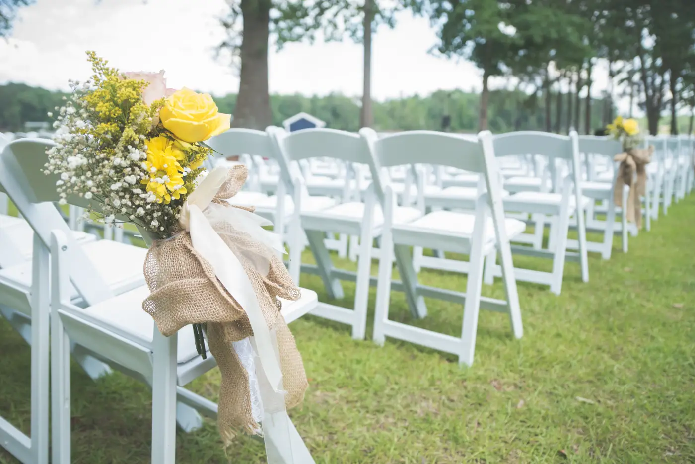 White padded chairs lined up for a garden wedding ceremony